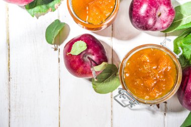 Ev yapımı altın sarısı elma reçeli, çiftlik kırmızı elmaları ve beyaz ahşap arka planda yapraklar kopyalama alanı