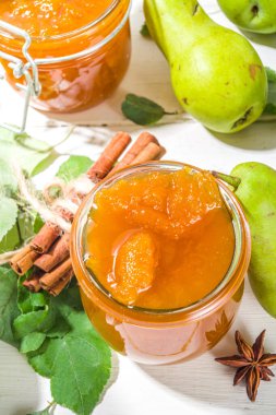 Ev yapımı altın renkli armut reçeli, beyaz ahşap arka plan üzerinde tarım armutları ve yaprakları kopyalama alanı