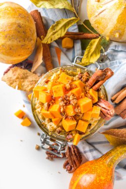 Sonbahar balkabağı cevizi yulaf ezmesi, bir gecede yulaf lapası tereyağı dilimleri, ceviz cevizi ve karamel sosu, beyaz ahşap arka plan fotokopi alanı.