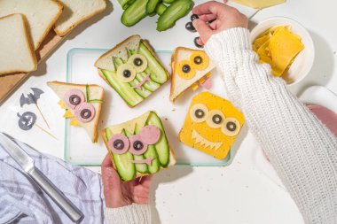 Çeşitli komik canavar Cadılar Bayramı sandviçleri. Kreatif kahvaltı hazırlamak peynirli tost, Cadılar Bayramı çocukları parti yemekleri, resimli kadın eli üstte