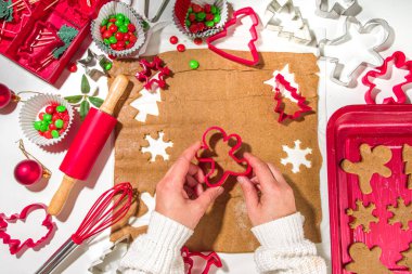 Noel, yeni yıl aşçılık geçmişi. Pişirme malzemeleri ve kap kacak - zencefilli ekmek hamuru, kurabiye keskisi, merdane. Kadın elleri şenlikli Xmas kurabiyeleri yapıyor parlak kırmızı beyaz konsept