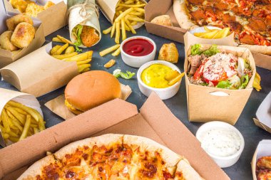 İnternetten fast food siparişi vermek. Muhtelif yemek takımları pizza, patates kızartması, kızarmış tavuk nugget, hamburger, salata, tavuk kanadı, kenarlar, siyah beton arka plan.
