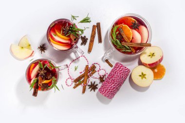 Ev yapımı sıcak şarap kokteyli. Klasik kış baharatlı sıcak sıcak sıcak şaraplı çeşitli cam bardaklar, beyaz arka plandaki malzemeler üst görünüm kopya alanı