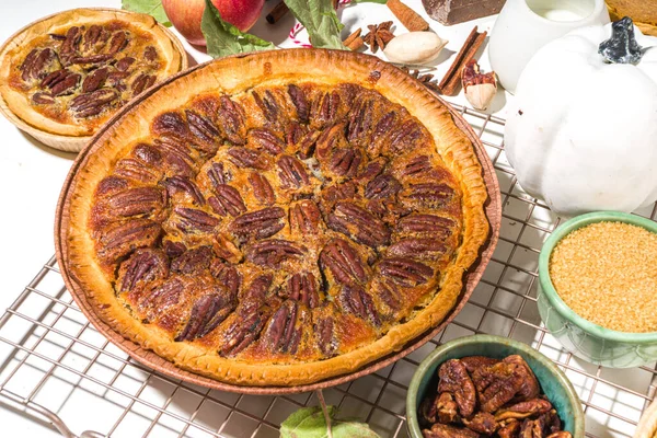 Autumn pie and cakes baking background. Sweet apple, pecan, pumpkin squash pies with baking ingredients and utensils, white table background top view copy space