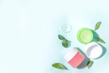 Su damlaları, kabarcıklar ve yeşil yapraklı kozmetik şişesi. Nemlendirici, yüz bakımı, onarım ve cilt bakımı ürünü. Üst görünüm Flaylay kopyalama alanı