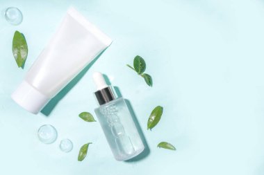 Su damlaları, kabarcıklar ve yeşil yapraklı kozmetik şişesi. Nemlendirici, yüz bakımı, onarım ve cilt bakımı ürünü. Üst görünüm Flaylay kopyalama alanı