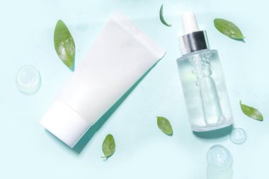 Su damlaları, kabarcıklar ve yeşil yapraklı kozmetik şişesi. Nemlendirici, yüz bakımı, onarım ve cilt bakımı ürünü. Üst görünüm Flaylay kopyalama alanı