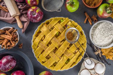 Sonbahar elmalı turta pişirme geçmişi. Çiğ geleneksel elmalı turta, fırın malzemeleri ve çatallar, siyah beton arka plan kopyalama alanı ile pişirme arka planı 