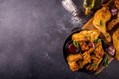 Izgara tavuk bacağı ve kanatları, baharatlar, sarımsak ve barbekü sosu, koyu beton masa arkaplan fotokopi alanı