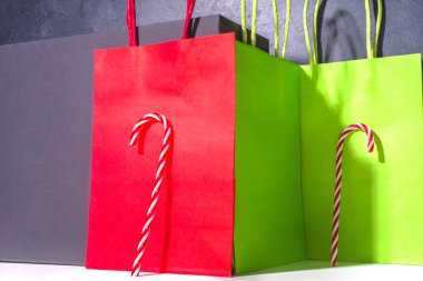 Sert gölgeli basit grafikli modern Noel tasarımı. Şeker kamışı tatlısı dikey olarak kırmızı yeşil arka plana dayanır. Alışveriş için kağıt torbalar, Noel Kara Cuma indirimi konsepti fotokopi alanı