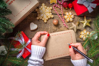 Noel hediyesi kutusu paketi. Noel hediyesi alışverişi konsepti covid-19 salgınında. Gizli Noel Baba oyunu. Paketleme hediyeleri, pakette kurabiyeler. Ahşap arkaplan, Xmas ağaç dalı ve dekoruyla