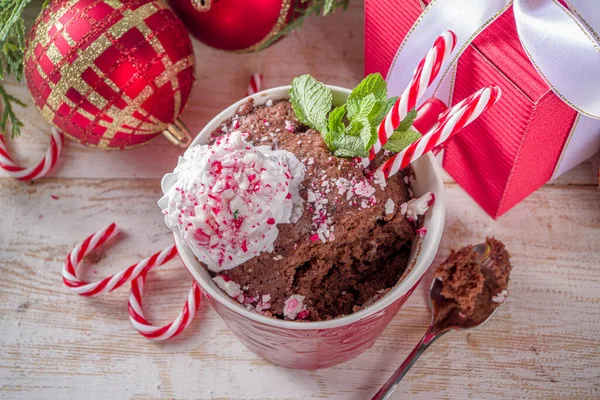 チョコレートペパーミント マグケーキ シンプルなクリスマスの朝食 軽食のアイデアのレシピ ホイップクリームとキャンディーの杖の作品がトッピングされたお祝いのマグカップのダークチョコレートケーキ — ストック写真