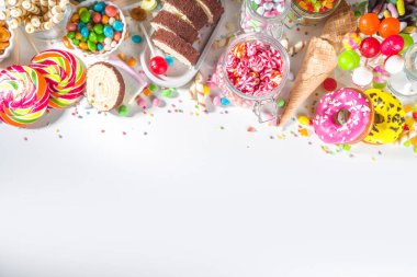 Renkli şekerlerden seç. Çeşitli şeker setleri, çikolatalar, çörekler, kurabiyeler, lolipoplar, beyaz arka planda dondurma üst görünümü