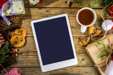 Noel Baba 'nın elinde tablet, noel süsü ve bir sürü hediye kutusu, dilek listesi ve Noel arkaplanı hazırlığı, online hediye alma konsepti.