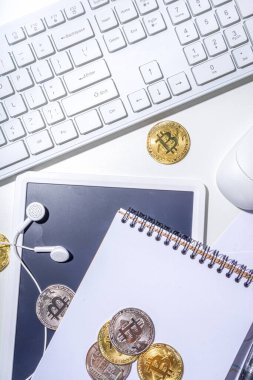 Ofis masaüstü çalışma alanındaki bitcoin paralar. Kripto para piyasası konseptiyle çalışmak. Klavye, dizüstü bilgisayar, tablet, fare, büyüyen bitcoin oranının grafikleri beyaz ofis masasında, üst görünüm kopyalama alanı