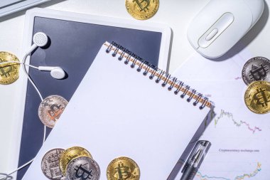 Ofis masaüstü çalışma alanındaki bitcoin paralar. Kripto para piyasası konseptiyle çalışmak. Klavye, dizüstü bilgisayar, tablet, fare, büyüyen bitcoin oranının grafikleri beyaz ofis masasında, üst görünüm kopyalama alanı