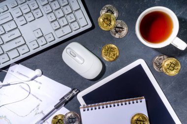 Ofis masaüstü çalışma alanındaki bitcoin paralar. Kripto para piyasası konseptiyle çalışmak. Klavye, dizüstü bilgisayar, tablet, fare, büyüyen bitcoin oranı grafikleri, siyah ofis masasında, üst görünüm kopyalama alanı