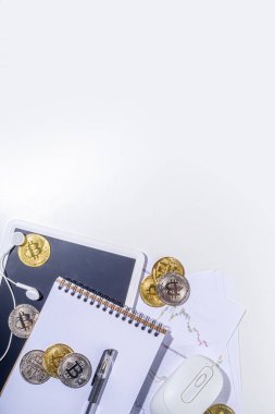 Ofis masaüstü çalışma alanındaki bitcoin paralar. Kripto para piyasası konseptiyle çalışmak. Klavye, dizüstü bilgisayar, tablet, fare, büyüyen bitcoin oranının grafikleri beyaz ofis masasında, üst görünüm kopyalama alanı
