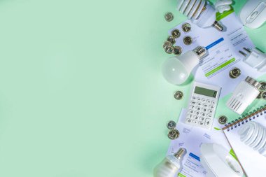 Modern modernleşme teknolojisi ve cihazlarıyla enerji tasarrufu. Elektrik faturaları, LED ampuller, ısı termostatı, açık yeşil masa fotokopi alanındaki hesap makinesi. Yeşil olsun, enerji maliyetleri kavramı