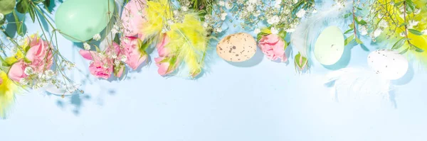 イースターの卵とイースターの春の背景 カラフルな羽 花や緑の葉 高色の明るい日当たりの良い青の背景 トップビューフレーム — ストック写真