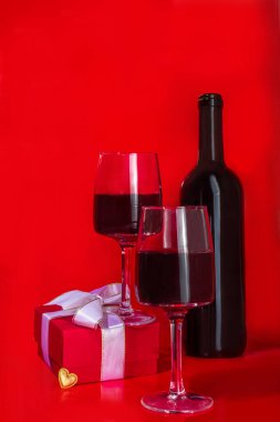 Sevgililer günü hediye kutusu ve şarap kadehleri, kırmızı arka plan üzerinde altın kalp dekoru olan fotokopi alanı