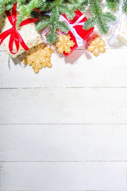 Geleneksel Noel tebrik kartı geçmişi. Beyaz ve kırmızı hediye kutuları, şenlikli kurdeleler, ev yapımı zencefilli kurabiyeler ve Noel ağacı dalları, beyaz ahşap arka plan kopyalama alanı.