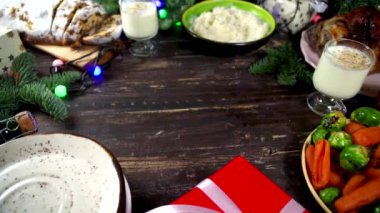 Geleneksel yiyeceklerle, fırınlanmış jambonla, tavukla, kızarmış havuçla, Brüksel lahanasıyla, patatesle, Noel dekoruyla ve hediyelerle dolu Noel yemeği masası. 