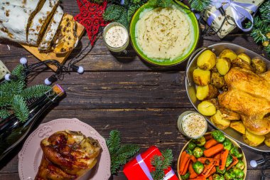 Geleneksel yiyeceklerle, fırınlanmış jambonla, tavukla, kızarmış havuçla, Brüksel lahanasıyla, patatesle, Noel dekoruyla ve hediyelerle dolu Noel yemeği masası.