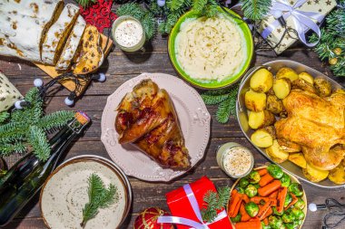 Geleneksel yiyeceklerle, fırınlanmış jambonla, tavukla, kızarmış havuçla, Brüksel lahanasıyla, patatesle, Noel dekoruyla ve hediyelerle dolu Noel yemeği masası.