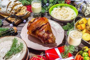 Geleneksel yiyeceklerle, fırınlanmış jambonla, tavukla, kızarmış havuçla, Brüksel lahanasıyla, patatesle, Noel dekoruyla ve hediyelerle dolu Noel yemeği masası.