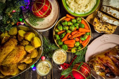 Geleneksel yiyeceklerle, fırınlanmış jambonla, tavukla, kızarmış havuçla, Brüksel lahanasıyla, patatesle, Noel dekoruyla ve hediyelerle dolu Noel yemeği masası.