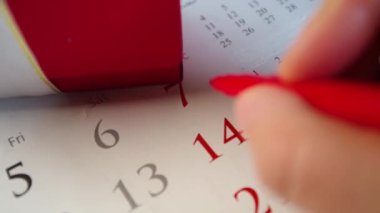 14 Şubat 'taki tatil takvimine kırmızı bir kalple yakın plan video çeken kız notları, kırmızı hediye kutusunun yanında. Sevgililer Günü tatili konseptine hazırlanılıyor