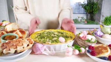 Kadınlar bayram yemeği hazırlar, Paskalya brunch 'ı. Geleneksel Paskalya yemekleri aile sofrasında - pişmiş et, kiş, bahar salatası, kek, renkli yumurta, sıcak haç çörekleri