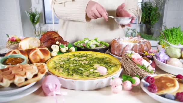 女性はお祝いの夕食 イースターブランチを準備します 家庭のテーブルの上の伝統的なイースター料理 焼き肉 キッシュ 春サラダ マフィン 色の卵 ホットクロスパン — ストック動画