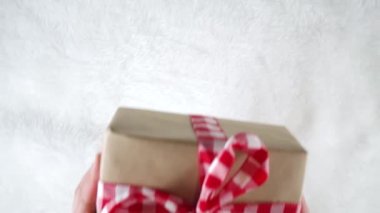 Kadın elleri yeni yıl hediyelerini süslüyor, el işi paketler şenlikli kurdeleler, beyaz kürk arka planda Noel ağacı dalları, düz bir üst görünüm