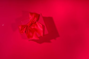 Sevgililer Günü tatili geçmişi. Kurdeleli el işi kağıt hediye kutusu, gül çiçekleri ve kalpler dekorasyonu, kırmızı arkaplan üst görünümü üzerinde kopyalama alanı