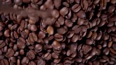 Kahve çekirdeklerini doldururken çekilmiş yakın çekim videosu, kavrulmuş kahverengi kahve çekirdekleri. 