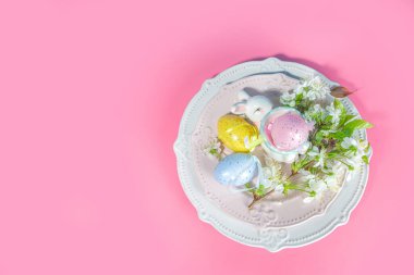 Paskalya sofrası dekorasyonu, renkli Paskalya yumurtaları, bahar bahçesi çiçekleri, tavşancık dekoru, yüksek renkli pembe arka plan fotokopi alanı.