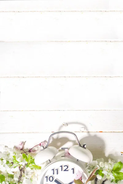 春の楽しみ時間 目覚まし時計と春の庭の光のコンセプト木製の背景にフラットレイコピースペース木製の白い背景に花 — ストック写真