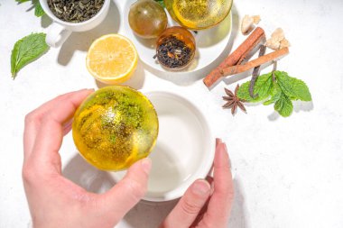 Modern çay topu bombalarıyla çay yapmak. Kurutulmuş çay, fincanlar, limon ve nane, klasik beyaz bardakla, üst görünüm kopyalama alanı