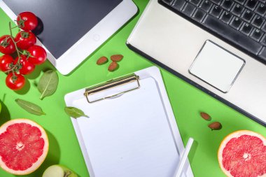 Yemek diyet planı konsepti, not defterinde, sağlıklı yiyecek meyveleri, sebzeler, tablet, not defterleri ve parlak yeşil masa arkaplanını sümüklendirmek için aksesuarlar ile