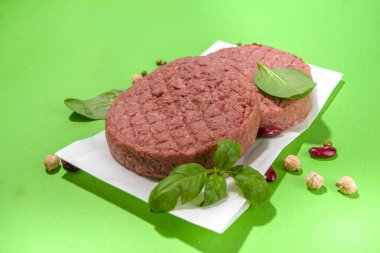Lab-grown or plant based burger cutlet, minced meat steaks over green background