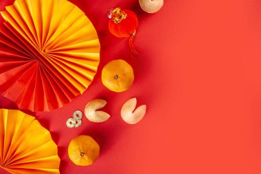 Çin 'in yeni yıl geçmişi. Geleneksel Çin Yeni Yıl dekoruna sahip kırmızı ve sarı düz yatak, dileklerle dolu zarflar, altın sikkeler, yelpazeler, Çin fenerleri, portakallar ve çay.