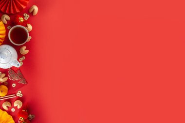 Çin 'in yeni yıl geçmişi. Geleneksel Çin Yeni Yıl dekoruna sahip kırmızı ve sarı düz yatak, dileklerle dolu zarflar, altın sikkeler, yelpazeler, Çin fenerleri, portakallar ve çay.