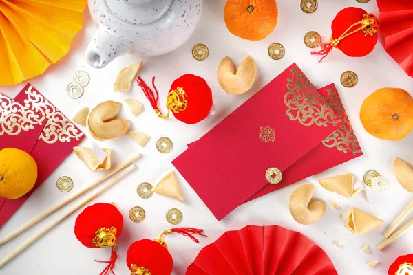 Chinese new year background. Red and golden yellow flatlay with traditional Chinese new year decor, envelopes with wishes, gold coins, fans, Chinese lanterns, oranges and tea