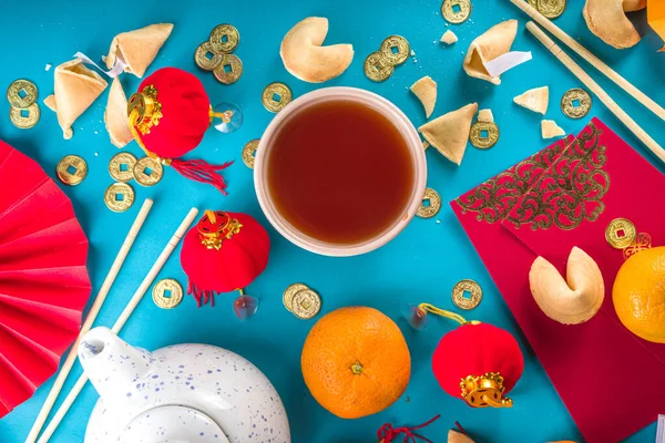 Chinese new year background. Red and golden yellow flatlay with traditional Chinese new year decor, envelopes with wishes, gold coins, fans, Chinese lanterns, oranges and tea