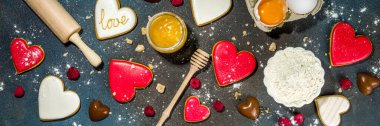 Sevgililer Günü tatlı aşçılık geçmişi. Fırın malzemeleri ve çatal bıçakları un, merdane, kalp şeklinde bisküviler, yumurta. Sevimli sevgililer günü hediyesi hazırlıyorum. Koyu mavi arkaplanda en üstteki görünüm kopyalama alanı