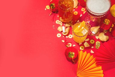 Çin Yeni Yıl Kokteyli içecekleri, üç farklı bardakta, çeşitli kırmızı altın rengi alkollü parti içecekleri, geleneksel Çin Yeni Yıl dekoru, karşılama zarfları, Çin fenerleri, bozuk paralar.