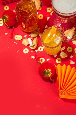Çin Yeni Yıl Kokteyli içecekleri, üç farklı bardakta, çeşitli kırmızı altın rengi alkollü parti içecekleri, geleneksel Çin Yeni Yıl dekoru, karşılama zarfları, Çin fenerleri, bozuk paralar.