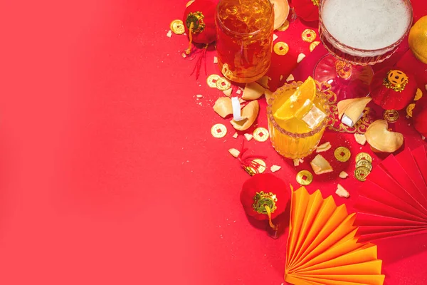 Çin Yeni Yıl Kokteyli içecekleri, üç farklı bardakta, çeşitli kırmızı altın rengi alkollü parti içecekleri, geleneksel Çin Yeni Yıl dekoru, karşılama zarfları, Çin fenerleri, bozuk paralar.